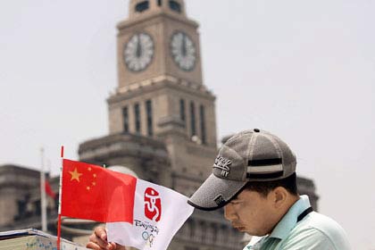 A man holds an Olympic flag yesterday at the Bund. The Beijing Olympic torch relay will be held in Shanghai tomorrow and on Saturday when traffic limits will be enforced. Century Park and the Shanghai Science and Technology Museum in Pudong will be closed tomorrow.