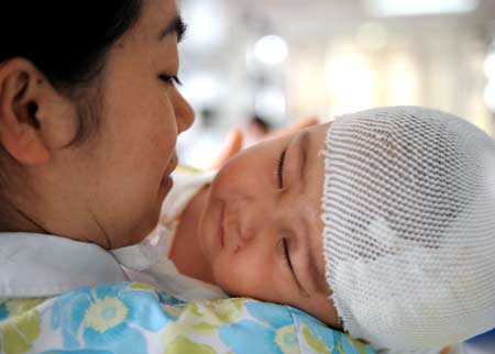 Seven-month-old Cao Wenxi sleeps in the arms of a nurse in the intensive care unit (ICU) of Xinqiao Hospital under the Third Military Medical University in Chongqing Municipality in southwest China, May 23, 2008. Cao Wenxi, injured in the May 12 quake in Mianzhu of southwest China, was given an operation in the hospital. He gained 1,500 grams and is in good condition, according to the hospital workers. 