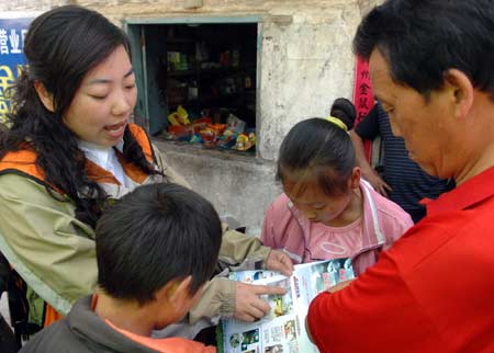 A medical worker (L) from east China's Zhejiang Province distributes brochures on epidemic prevention at Qinggang Village, Gucheng Town, Pingwu County, in southwest China's Sichuan Province, on May 23, 2008. Large numbers of medical workers have arrived at local villages in the quake-hit area in Sichuan Province to provide medical treatment and health services. 