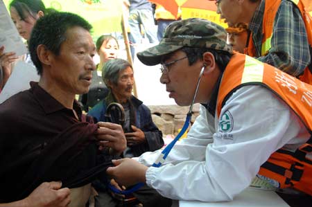 A medical worker (R) from east China's Zhejiang Province examines a local man at Qinggang Village, Gucheng Town, Pingwu County, in southwest China's Sichuan Province, on May 23, 2008. Large numbers of medical workers have arrived at local villages in the quake-hit area in Sichuan Province to provide medical treatment and health services. 