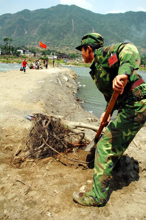 A soldier clears obstacles at the bridge in Nanba Town of Pingwu County under Mianyang City, southwest China's Sichuan Province, May 22, 2008. The only bridge in Nanba Town was destroyed in the May 12 quake mainly hitting Sichuan Province. Soldiers of the Chinese People's Liberation Army built a floating bridge instead within three days, which speed up the rescue work in the area. 