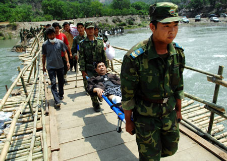Soldiers carrying a man injured in the May 12 quake walk on the newly built floating bridge in Nanba Town of Pingwu County under Mianyang City, southwest China's Sichuan Province, May 22, 2008. The only bridge in Nanba Town was destroyed in the May 12 quake mainly hitting Sichuan Province. Soldiers of the Chinese People's Liberation Army built a floating bridge instead within three days, which speed up the rescue work in the area. 