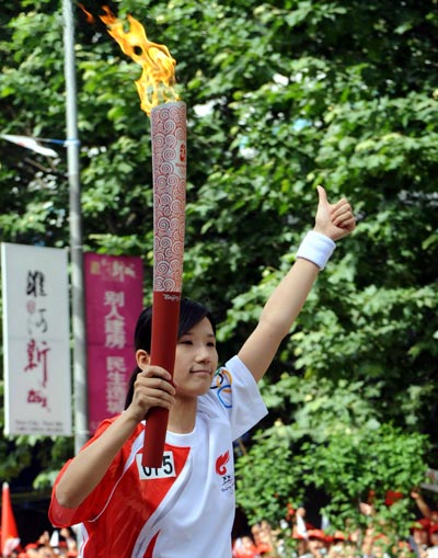 Photo: A torchbearer gestures for the victory of Olympic torch relay in Huainan
