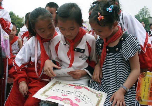 Ouyang Ruke, a girl from earthquake-hit Guanghan city in southwestern China's Sichaun Province, shares her commendation with two of her new classmates in Fuquan city in southwestern China's Guizhou Province on Thursday, May 29, 2008. 