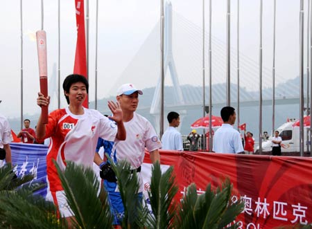 Torchbearer Li Ting (L) runs with the torch during the 2008 Beijing Olympic Games torch relay in Yichang, Central China&apos;s Hubei Province, May 31, 2008.