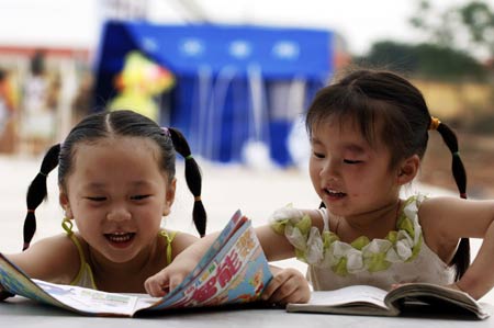 Zhang Yumei (L) and Tu Lingwen read books in front of a tent in the quake-hit Deyang of southwest China's Sichuan Province, May 31, 2008. Children in the quake-hit areas will celebrate the International Children's Day which falls on June 1 in tents. 