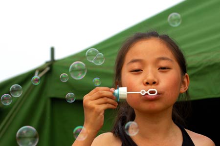 Yang Jiayun blows soap bubbles in front of a tent in the quake-hit Deyang of southwest China's Sichuan Province, May 31, 2008. 