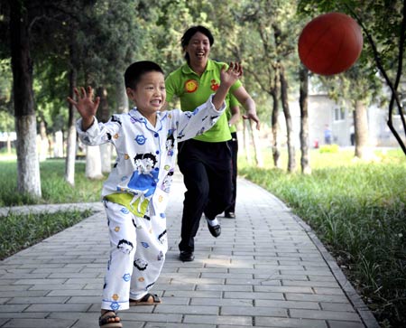 Liao Yu (front), a quake-wounded boy from the quake-hit Deyang of southwest China's Sichuan Province, plays basketball with volunteers in Beijing geriatric hospital in Beijing, May 31, 2008. More than 10 children from quake-hit Sichuan Province treated in Beijing geriatric hospital will celebrate the International Children's Day in Beijing. 