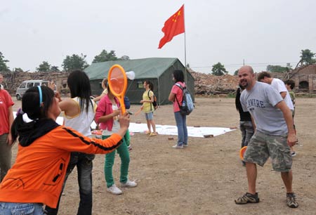 A pupil plays badminton with a Canadian volunteer on the playground in a primary school in Dongbei Town, Mianzhu City, southwest China's Sichuan Province, May 31, 2008. 