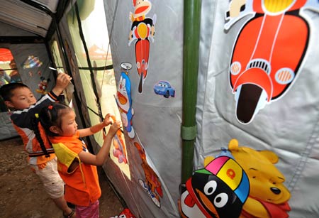 Pupils decorate their tent classroom in a primary school in Dongbei Town, Mianzhu City, southwest China's Sichuan Province, May 31, 2008.