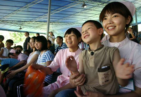 Injured children from the quake-ravaged Mianyang City of Sichuan Province, watch animal performance with nurses at a safari park in southwest China's Chongqing Municipality, May 31, 2008. 