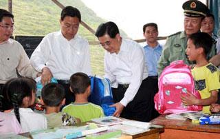 Chinese President Hu Jintao (C) sends stationery to children and wishes them a happy Children's Day in a tent school in Jinshansi Village, Guangping Town, Ningqiang County, Shaanxi Province, northwest China, May 31, 2008. Hu Jintao arrived in Shaanxi Province on Saturday morning to oversee quake relief operations. (Xinhua Photo)