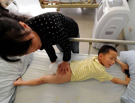 7-year-old Zeng Pengfei is massaged by his mother at a hospital in Chengdu, capital of southwest China's Sichuan Province, May 31, 2008. The International Children's Day falls on June 1. Children in quake-hit areas in China are optimistic about their future. 