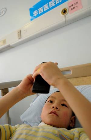 7-year-old Zeng Pengfei play cellphone games at a hospital in Chengdu, capital of southwest China's Sichuan Province, May 31, 2008.