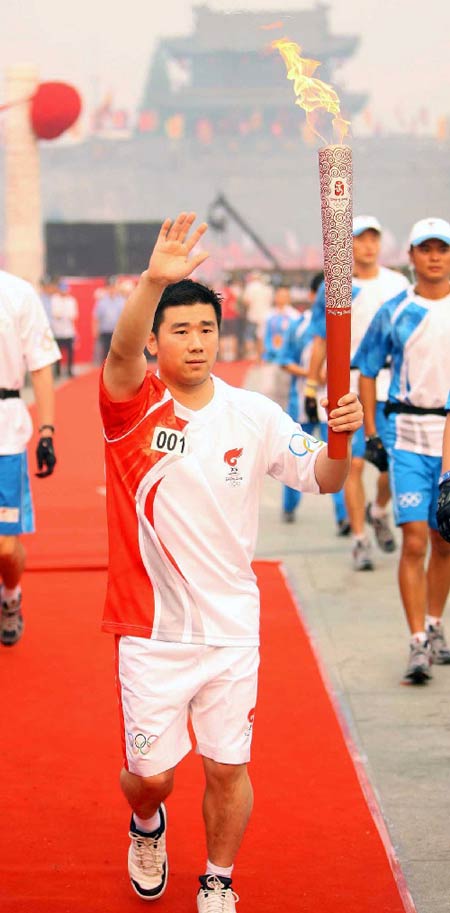 Photo: Torchbearer Zheng Lihui waves while running with the torch