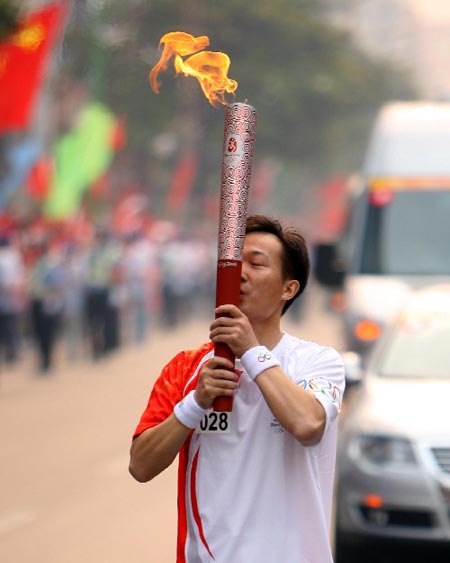 Photo: Torchbearer Li Caisheng kisses the torch