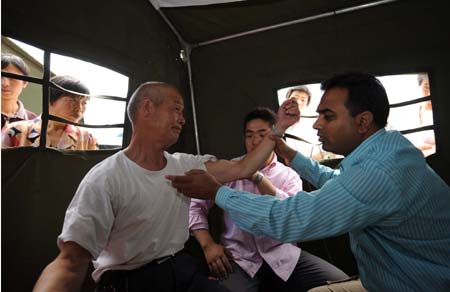 A member (R) of the Pakistani medical team does medical checkup for a man in the Wudu District of Longnan City, northwest China's Gansu Province, June 2, 2008. The 28-member Pakistani medical team has set up a tent hospital in quake-hit Longnan after it arrived in the city on May 29. 