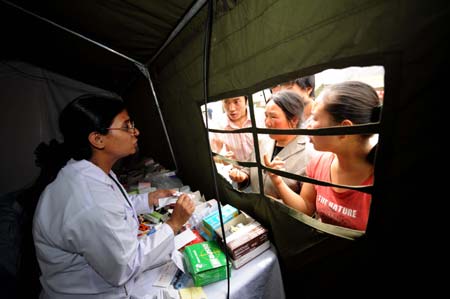 A member (L) of the Pakistani medical team explains to people the usage of the medicine in the Wudu District of Longnan City, northwest China's Gansu Province, June 2, 2008. The 28-member Pakistani medical team has set up a tent hospital in quake-hit Longnan after it arrived in the city on May 29.