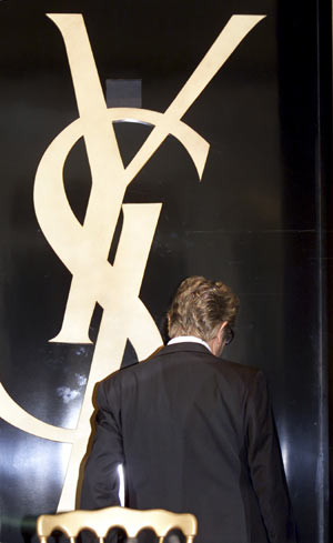 Fashion designer Yves Saint Laurent leaves the room after a news conference at which he announced his retirement in Paris in this January 7, 2002 file photo.