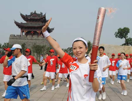 Photo: Torchbearer Qiu Xiao(R) waves to people in Yueyang