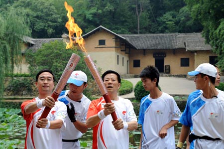 Torchbearer Mao Yushi (L3) passes the flame to the next torchbearer Xie Zhenhua in front of the Former Residence of Chairman Mao Zedong during the 2008 Beijing Olympic Games torch relay in Shaoshan, known as the hometown of Mao Zedong, central China's Hunan Province, June 5, 2008. 