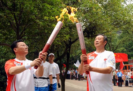 Torchbearer Mao Anping(R), son of Chairman Mao's cousin Mao Zelian, passes the flame to the next torchbearer Huang Zhigang during the 2008 Beijing Olympic Games torch relay in Shaoshan, known as the hometown of Mao Zedong, central China's Hunan Province, June 5, 2008.