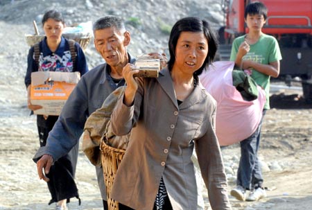 Residents carry their belongings to temporary plank houses at Huilong Village in Qingchuan County, southwest China's Sichuan Province, June 5, 2008. Around 500 quake-affected residents moved to temporary plank houses in Qingchuan County on June 5. 