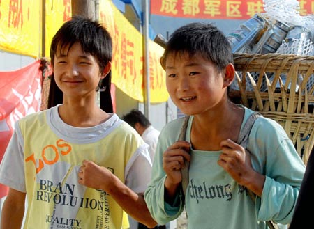 Two children carry their belongings to to temporary plank houses at Huilong Village in Qingchuan County, southwest China's Sichuan Province, June 5, 2008. 