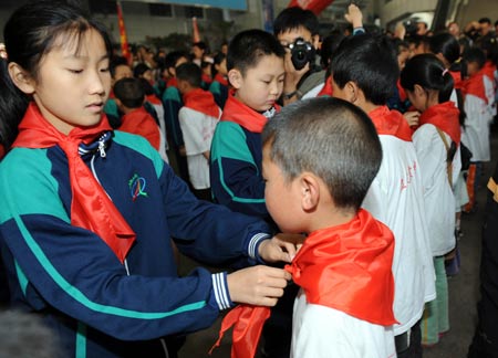 Students of Mingzhu Primary School tie red scarves for students from the quake-hit Sichuan Province in southwest China, in Jinan, capital of east China's Shandong Province, June 5, 2008. A total of 809 students from Leigu Town of Sichuan's Beichuan County, one of the most serious quake-hit areas, arrived in Jinan Thursday to restart their study in four schools. 