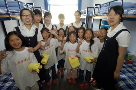 Students from the quake-hit Sichuan Province in southwest China pose for a photo with volunteers in their dormitory in Jinan, capital of east China's Shandong Province, June 5, 2008.