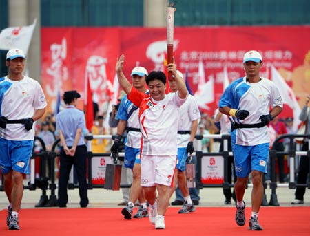 Torchbearer Wu Shude waves to people while running during the launching ceremony of the 2008 Beijing Olympic Games torch relay in Nanning, southwest China's Guangxi Zhuang Autonomous Region, June 7, 2008.