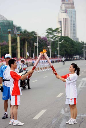 Torchbearer and Olympic gold medal winner Mo Huilan(R) passes the Olympic flame to her successor Li Mingkun during the 2008 Beijing Olympic Games torch relay in Nanning, southwest China's Guangxi Zhuang Autonomous Region, June 7, 2008.