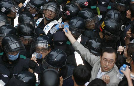 Protestors give bottles of water to riot policemen as they confront each other during a march toward the presidential Blue House in Seoul after a candle-light vigil June 7, 2008.