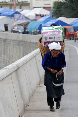 A woman carries food supplies in Wenchuan County, southwest China's Sichuan Province, June 8, 2008. Victims living in the epicenter town Wenchuan started to regain their normal life as a month past since the deadly earthquake struck southwest China's Sichuan Province.