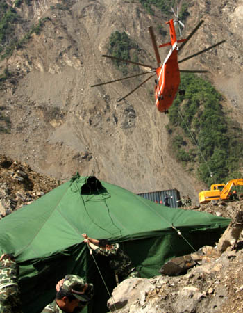  A Mig-26 helicopter carries materials while soldiers hold the tent to prevent it from being blown away by the strong air current due to the operation of the helicopter at the Tangjiashan quake-formed lake in southwest China's Sichuan Province, May 9, 2008. The drainage plus natural leakage of the lake was about 48 cubic meters per second, a hydro expert said on Monday morning. The Chengdu Military Command of the People's Liberation Army sent an additional 120-strong team to blast boulders in the channel to accelerate drainage. 