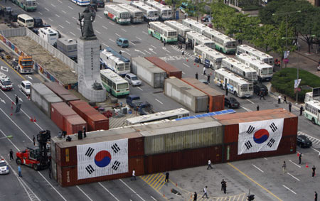 Police place South Korean flags on cargo containers that hold sand to form a barricade to block a planned protest march on a street leading to the U.S. embassy and the presidential Blue House in central Seoul June 10, 2008. The containers were welded together and on to the road. About one million people fearing infection of mad cow disease across the country will demonstrate Tuesday evening to demand full-scale renegotiation of a beef deal with the U.S. and the resignation of President Lee Myung-bak as they commemorate the historic June 10 mass pro-democracy demonstrations in 1987. 