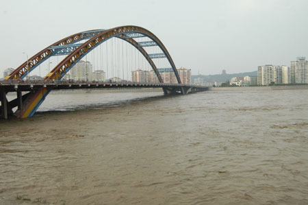 The torrents sluiced from the Tangjiashan quake lake, formed after quake-triggered landslides from the Tangjiashan Mountain blocked the Tongkou River, flow through the Peijiang River Bridge No.3 safe and sound, in Mianyang City, southwest China's Sichuan Province, June 10, 2008. The water level of the muds-, boulders- and large debris-blocked lake is lowered to safety-entailed 720 meters above sea level at the bottom of its drainage spillway. (Xinhua Photo)