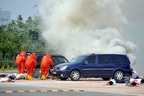 Security officers in orange protective suits investigate a simulated chemical explosion during an Olympic security drill outside the beach volleyball venue in the Chaoyang Park in Beijing on Wednesday, June 11, 2008. China launched a series of anti-terrorist drills at the national level on Wednesday to cope with threats to the upcoming Beijing Olympics.