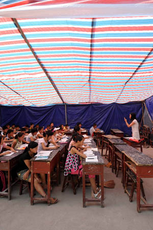 Sixth graders attend class in a tent at Chengguan No.2 elementary school in Wenxian county, Longnan city, northwest China's Gansu Province June 11, 2008. About 90 percent of the 2,964 middle schools and elementary schools suspended in the quake-hit Longnan city have resumed classes by now. The local government is still working hard to help reopen schools and kindergartens in remote villages and mountainous areas. 