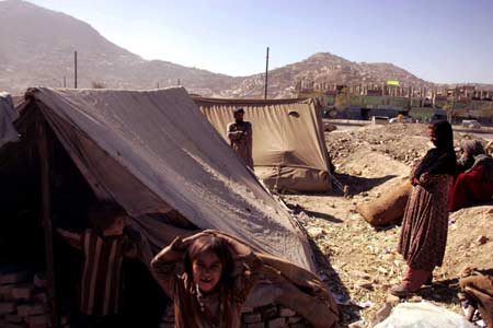 Afghan refugees stand around their tent at a camp in Kabul, capital of Afghanistan, June 11, 2008. Afghanistan government, in its effort to implement the Five-year Development Plan and alleviate poverty in the country, is going to appeal for 50 billion U.S. dollars at a donors conference for Afghanistan which will be opened on Thursday in Paris with the attendance of over 60 countries and organizations.