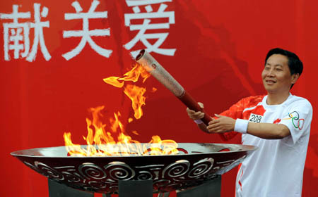 Torchbearer Yuan Zhou kindles the Olympic flame cauldron during the 2008 Beijing Olympic Games torch relay in Guiyang, capital of southwest China's Guizhou Province on June 12, 2008. 