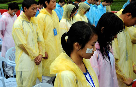 Local participants mourn for the victims of the earthquake that struck Sichuan province on May 12 at the launching ceremony of the 2008 Beijing Olympic Games torch relay in Guiyang, capital of southwest China's Guizhou Province on June 12, 2008. 