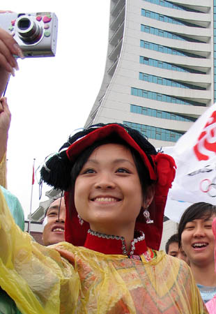 A girl dressed in the ethical costumes take photos during the 2008 Beijing Olympic Games torch relay in Guiyang, capital of southwest China's Guizhou Province on June 12, 2008. 