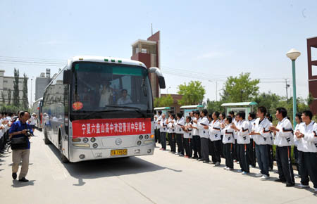 Buses carrying high school students from quake-affected Qingchuan County of southwest China's Sichuan Province are welcomed as they arrive at Liupanshan Higher Middle School in Yinchuan, capital of northwest China's Ningxia Hui Autonomous Region, on June 12, 2008. A total of 130 high shool students from Qingchuan will continue their studies at Ningxia Liupanshan Higher Middle School. Their school tuitions and daily costs are covered by the government of Ningxia Hui Autonomous Region.
