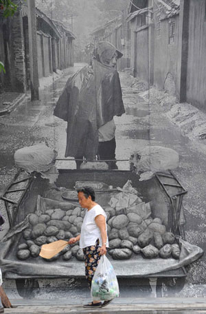 A woman walks past a painting at a historical culture preservation district in Chengdu, capital of southwest China's Sichuan Province, June 13, 2008. 