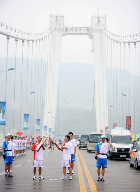 Photo: Two torchbearers hands over the Olympic flame in Wanzhou