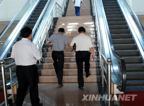  Workers climb the stairs as the escalator stands still in the office building of Weifang Municipal Government in Shandong Province on June 16, 2008. [Photo: xinhuanet]