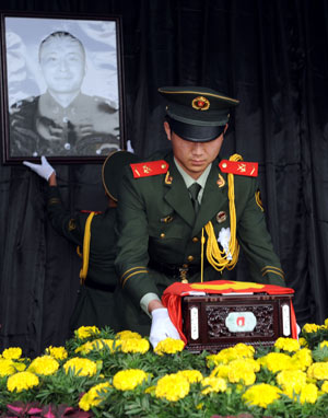 Armed policemen place the bone ash and picture of Zhang Peng, a crew member of the crashed helicopter on a quake relief mission on May 31, during his funeral in Tengzhou City, east China's Shandong Province, June 17, 2008. 