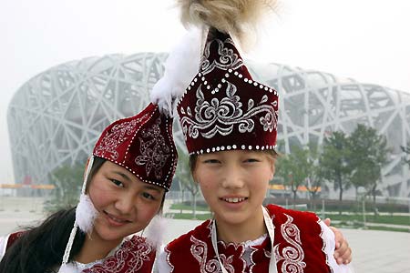 Two girls, from the Xinjiang Uygur autonomous region, pose in front of the National Stadium, or 'Bird's Nest,' June 19, 2008. Fifty-six ambassadors of China's 56 ethnic groups, most with a physical disability, will enjoy the host city in a five-day 'Olympic Tour' event until June 23. 