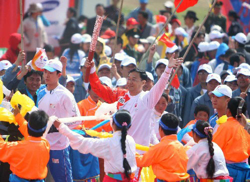 Surgeon Daga, the first torchbearer of the leg, waves to the cheering people while running the first segment on Monday, June 23, 2008. [Photo: Xinhua]